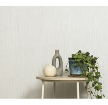 Gestructureerd behang met verticaal streepmotief in een lichte woonruimte met een bijzettafel, twee vazen en een hangplant.