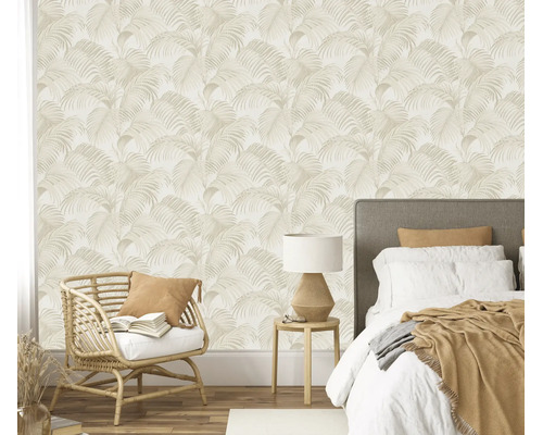 Vliesbehang met palmbladpatroon in een slaapkamer met rotan fauteuil en tweepersoonsbed.