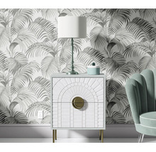 Woonkamer met vliesbehang met palmbladerenmotief, nachtkastje met Art Deco ontwerp en tafellamp voor een muur.