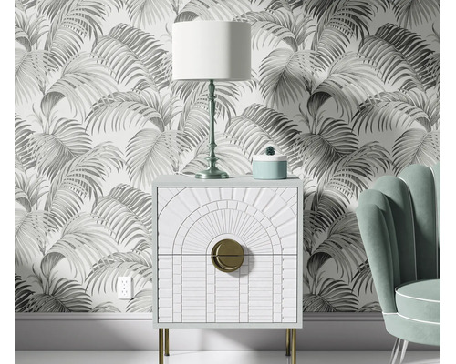 Woonkamer met vliesbehang met palmbladerenmotief, nachtkastje met Art Deco ontwerp en tafellamp voor een muur.