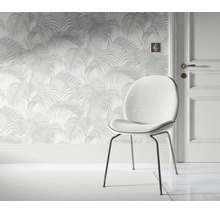 Vliesbehang met palmbladeren patroon voor een deur met een ronde gestoffeerde stoel in een lichte en stijlvolle woonruimte.