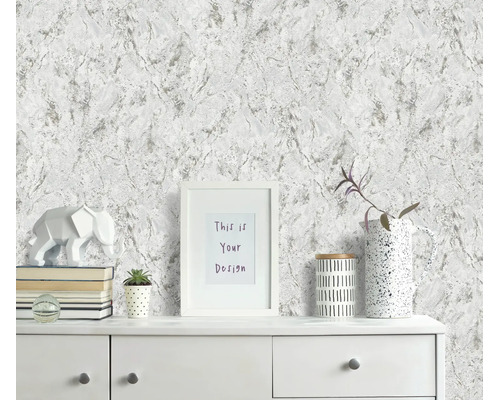 Woonkamerontwerp met vliesbehang in marmerlook en moderne decoratie op een witte ladekast.