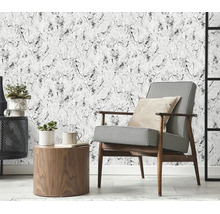 Woonkamer met vliesbehang in marmerlook, gecombineerd met een fauteuil met hanenpotmotief, houten tafel en decoratieve planten.