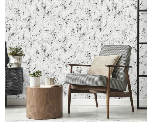 Woonkamer met vliesbehang in marmerlook, gecombineerd met een fauteuil met hanenpotmotief, houten tafel en decoratieve planten.