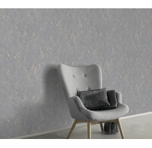 Gestructureerd vliesbehang met marmerlook achter een fauteuil in een modern interieur.