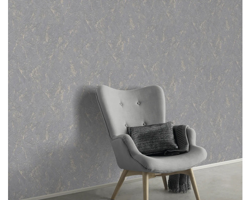 Gestructureerd vliesbehang met marmerlook achter een fauteuil in een modern interieur.
