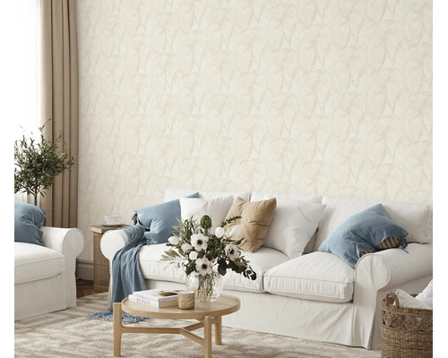 Woonkamer met licht vliesbehang met subtiel bladpatroon achter een witte bank en een ronde houten tafel met bloemenvaas.