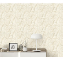 Vliesbehang met tropisch bladpatroon in een woonruimte met dressoir en tafellamp voor een muur met behangpatroon.