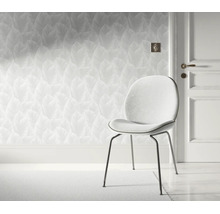 Modern behang met bladerpatroon in een lichte kamer met een elegante stoel en een kamerdeur.