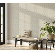 Woonruimte met vliesbehang met ginkgo bladmotief op de muur, een houten bank met kussens en een kamerplant.