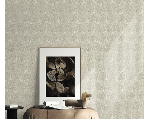 Gestructureerd vliesbehang met waaierpatroon als wanddecoratie in een woonkamer met fotolijst en decoratief figuur op een zitmeubel.