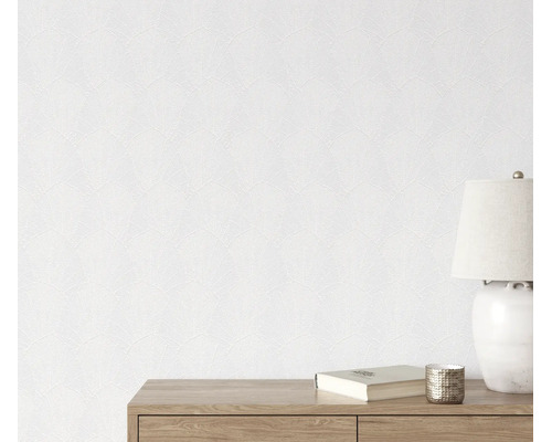 Gestructureerd vliesbehang met waaierachtig bladmotief op een muur, gecombineerd met een dressoir, een tafellamp en een boek.