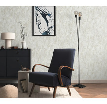 Woonkamer met gestructureerd vliesbehang, donkerblauwe retro fauteuil, zwarte ladekast, bijzettafel, vloerlamp en wanddecoratie.