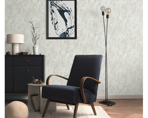 Woonkamer met gestructureerd vliesbehang, donkerblauwe retro fauteuil, zwarte ladekast, bijzettafel, vloerlamp en wanddecoratie.
