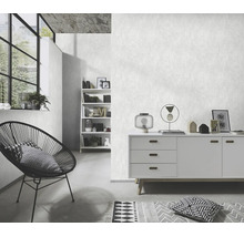 Woonkamer met gestructureerd vliesbehang, modern dressoir, stoel met draadframe en open wandrek in minimalistische woonstijl.