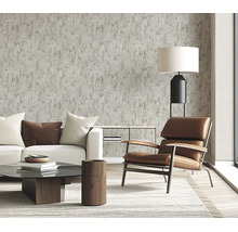 Woonkamer met vliesbehang in betonlook, modern ingericht met lederen fauteuil, bank en salontafel in een lichte en huiselijke sfeer.