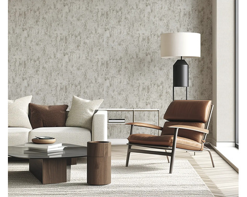 Woonkamer met vliesbehang in betonlook, modern ingericht met lederen fauteuil, bank en salontafel in een lichte en huiselijke sfeer.