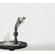 Gestructureerd behang in een moderne woonkamer met een kleine ronde tafel, decoratieve vaas en glas