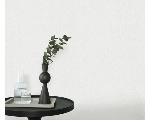 Gestructureerd behang in een moderne woonkamer met een kleine ronde tafel, decoratieve vaas en glas