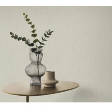 Getextureerd behang in een modern interieur met een kleine bijzettafel, glazen vaas en een eucalyptus tak.