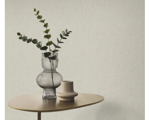 Getextureerd behang in een modern interieur met een kleine bijzettafel, glazen vaas en een eucalyptus tak.