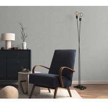 Woonkamer met gestructureerd vliesbehang, een fauteuil met houten armleuningen, een dressoir en een staande lamp in een modern interieur.