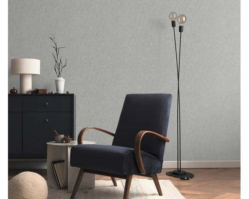 Woonkamer met gestructureerd vliesbehang, een fauteuil met houten armleuningen, een dressoir en een staande lamp in een modern interieur.