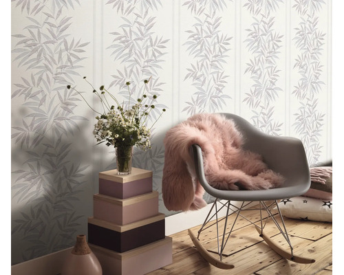 Woonkamer met vliesbehang met bamboepatroon en strepen, een schommelstoel en een decoratieve zuil van gestapelde houten kisten.