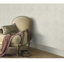 Gestructureerd vliesbehang op een muur gecombineerd met een antieke gestoffeerde fauteuil en een deken in een klassieke woonkamer.