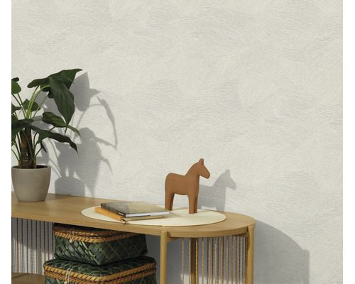 Gestructureerd vliesbehang op een muur met een console, plant en decoratie in een lichte woonruimte.