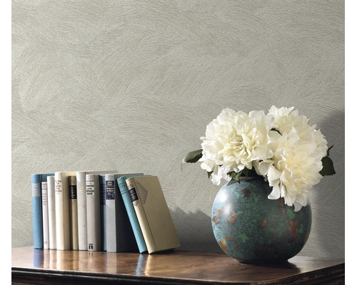 Getextureerd vliesbehang met veegstructuur als achtergrond voor een boekenplank met boeken en een vaas met bloemen.
