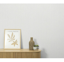 Gestructureerd vliesbehang voor een muur met een houten kast, een ingelijste afbeelding en kleine planten.