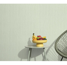 Vliesbehang met fijne lijnenstructuur bij een kleine bijzettafel met fruitschaal en een moderne stoel.