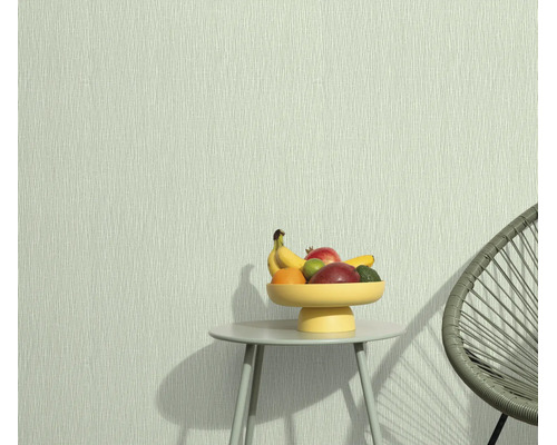 Vliesbehang met fijne lijnenstructuur bij een kleine bijzettafel met fruitschaal en een moderne stoel.