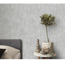 Gestructureerd vliesbehang in een moderne woonkamer met bed en bijzettafel met olijfboom.