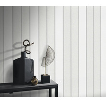 Gestructureerd behang met verticaal streeppatroon op een muur, gedecoreerd met een dressoir en woonaccessoires.