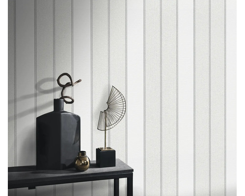 Gestructureerd behang met verticaal streeppatroon op een muur, gedecoreerd met een dressoir en woonaccessoires.