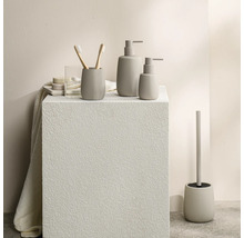 Moderne badkameraccessoireset met zeepdispensers, tandenborstelhouder en toiletborstelset in een minimalistische steenlook.