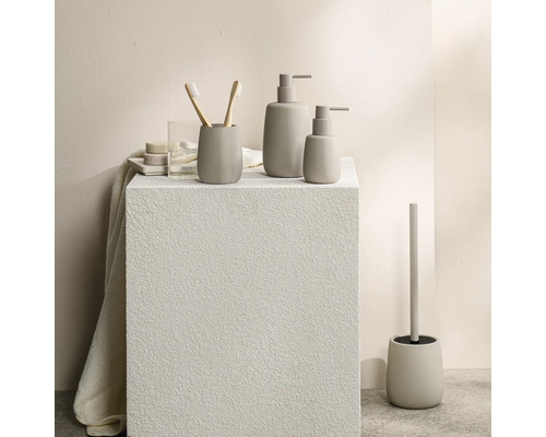 Moderne badkameraccessoireset met zeepdispensers, tandenborstelhouder en toiletborstelset in een minimalistische steenlook.