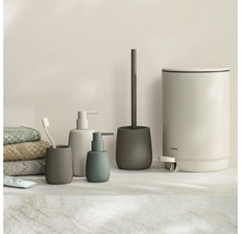 Moderne badkameraccessoireset bestaande uit zeepdispensers, tandenborstelhouder, toiletborstelhouder en pedaalemmer in mat design naast handdoeken.