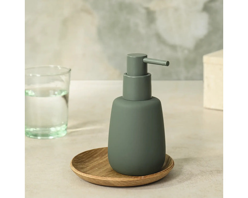 Moderne matte zeepdispenser in donkergroen op een klein houten schaaltje.