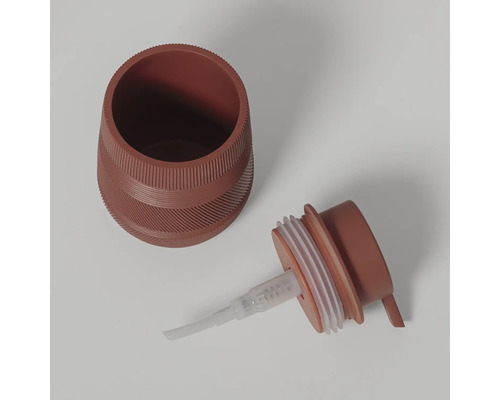 Terracotta-kleurige zeepdispenser van kunststof met gestructureerd oppervlak, tweedelig met reservoir en pompkop.