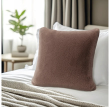 Vierkant sierkussen in imitatiebontlook op een bed met een deken en kussens op de achtergrond.