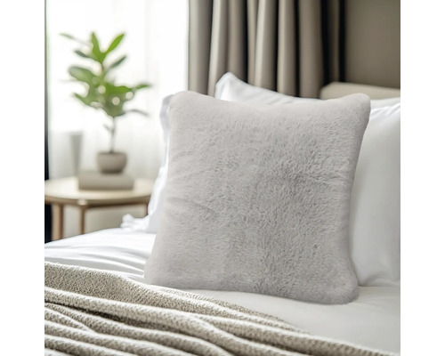 Zacht sierkussen van imitatiebont op een bed in een lichte slaapkamer.