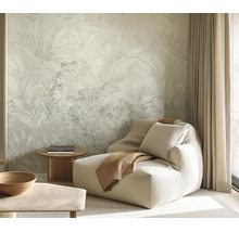 Woonkamer met vliesbehang met floraal bladerpatroon, comfortabele fauteuil, bijzettafel en gordijnen voor een rustige sfeer.