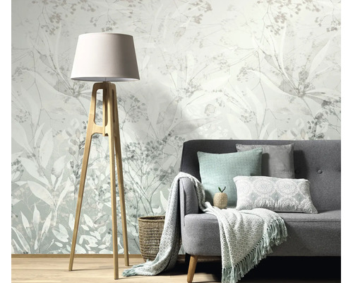 Woonkamer met vliesbehang met botanisch plantenpatroon, een grijze bank en een staande lamp met houten frame.