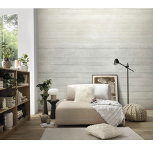 Woonkamer met vliesbehang in betonlook met horizontale strepenstructuur, gecombineerd met houten rek, loungemeubel en textielaccessoires.