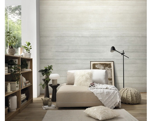 Woonkamer met vliesbehang in betonlook met horizontale strepenstructuur, gecombineerd met houten rek, loungemeubel en textielaccessoires.