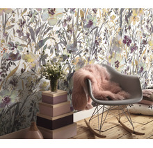 Woonruimte met vliesbehang met bloemenpatroon, een schommelstoel met een zachte vacht, houten opbergdozen en een boeket bloemen.