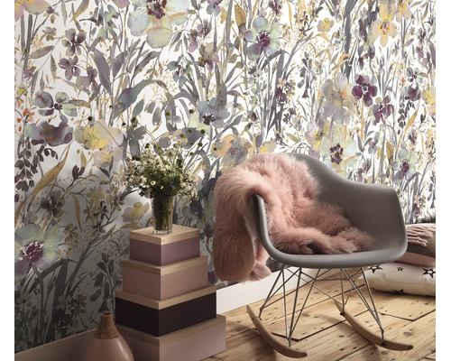 Woonruimte met vliesbehang met bloemenpatroon, een schommelstoel met een zachte vacht, houten opbergdozen en een boeket bloemen.